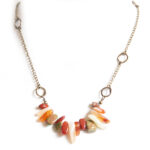 A gemstone tumble of aloe shades, on an antique brass chain, with asymmetrical brass features.